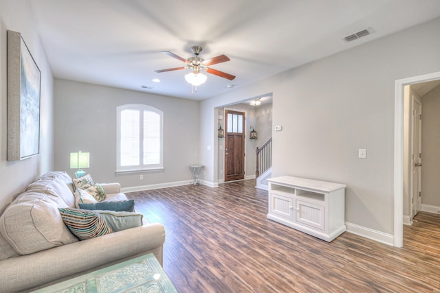 living area with stairway, wood finished floors, visible vents, and baseboards