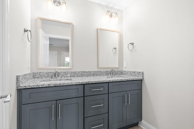 full bathroom with a sink, baseboards, and double vanity