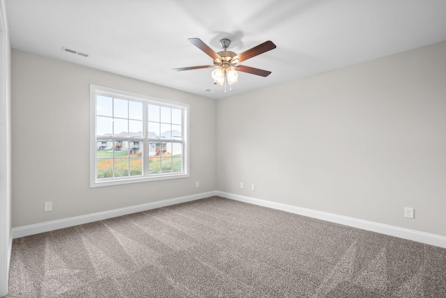 carpeted empty room with visible vents, baseboards, and ceiling fan