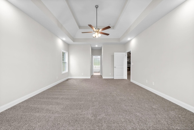 unfurnished bedroom with baseboards, a tray ceiling, carpet floors, recessed lighting, and ensuite bathroom