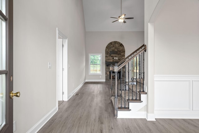 entryway with a ceiling fan, wood finished floors, a fireplace, baseboards, and stairs