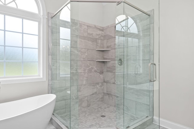 full bathroom featuring baseboards, a stall shower, and a freestanding bath