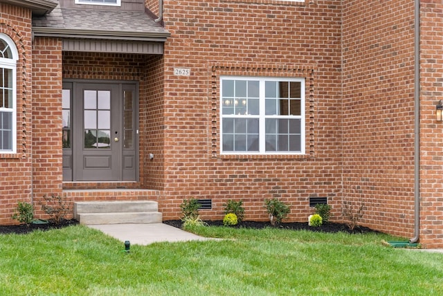 doorway to property featuring a shingled roof, brick siding, and crawl space