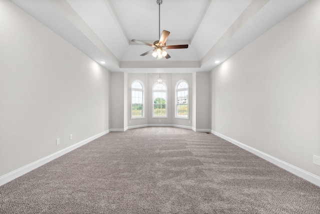 unfurnished room with baseboards, a raised ceiling, a ceiling fan, and carpet