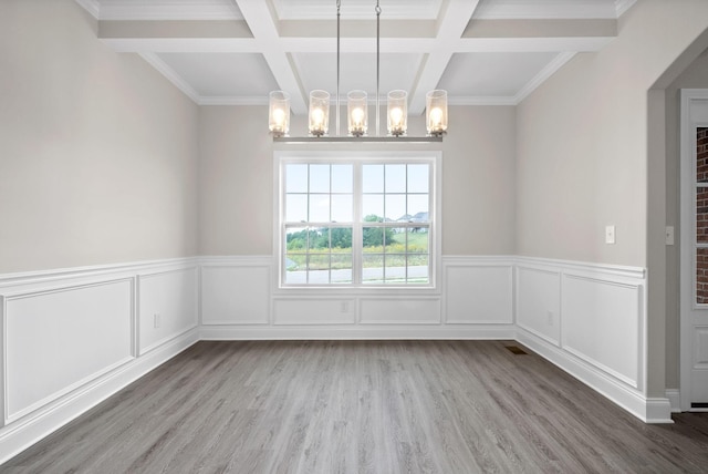 unfurnished dining area with beamed ceiling, a notable chandelier, wood finished floors, and coffered ceiling