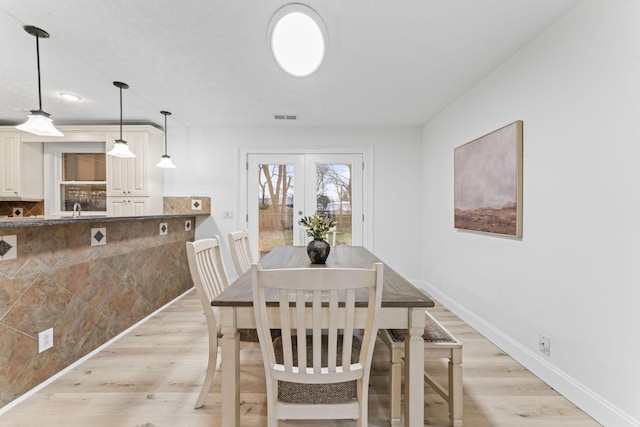 dining area featuring visible vents, french doors, light wood-type flooring, and baseboards