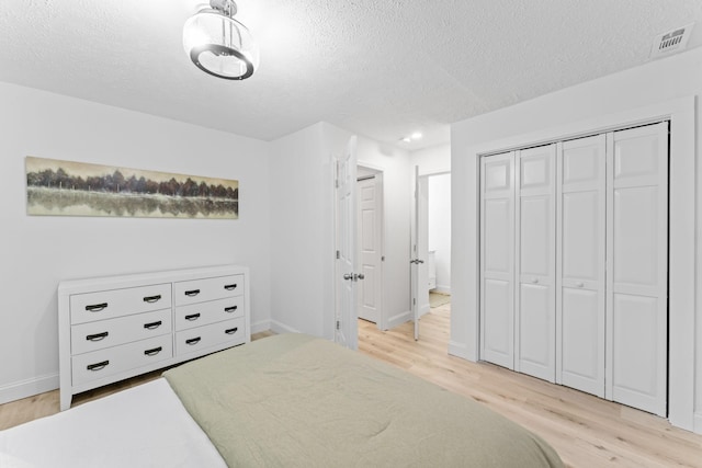 bedroom with visible vents, light wood-style flooring, and a textured ceiling