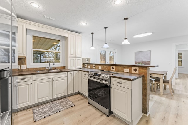 kitchen featuring dark countertops, light wood-style flooring, a peninsula, and appliances with stainless steel finishes