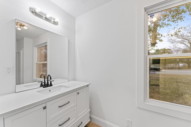 bathroom featuring a textured ceiling, vanity, and baseboards