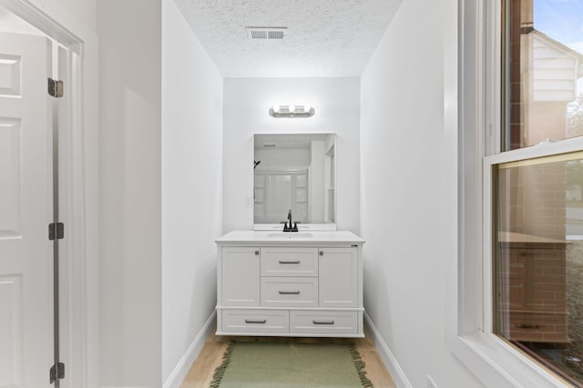 full bathroom featuring visible vents, baseboards, a textured ceiling, and vanity