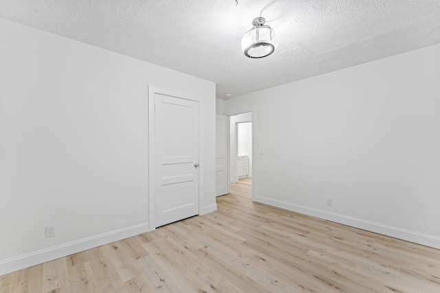 spare room with baseboards, a textured ceiling, and wood finished floors