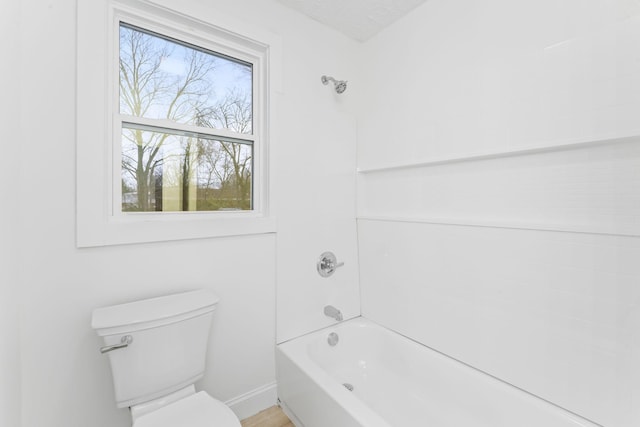 bathroom with baseboards, toilet, shower / bathtub combination, and a textured ceiling