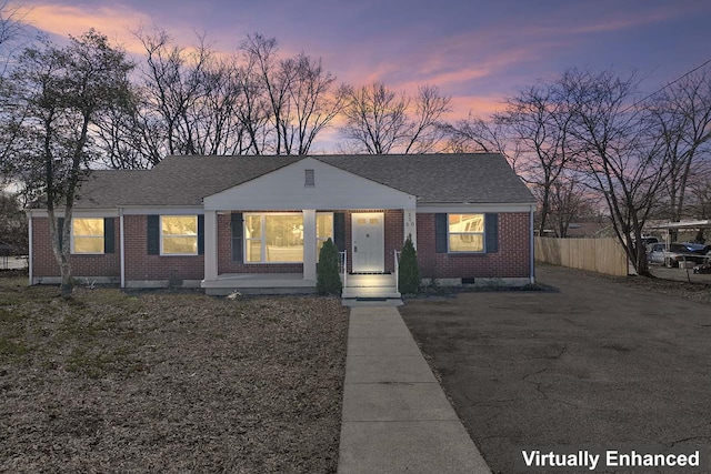 bungalow-style house featuring crawl space, roof with shingles, brick siding, and fence