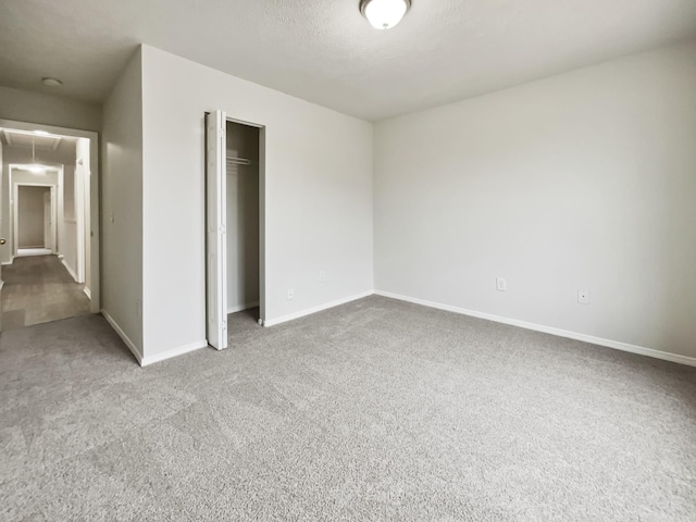 unfurnished bedroom featuring attic access, baseboards, a closet, and carpet floors