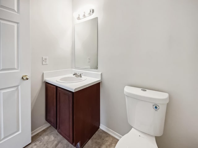 half bathroom with toilet, vanity, and baseboards