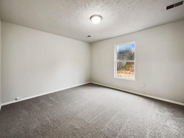 spare room featuring baseboards, visible vents, and dark carpet