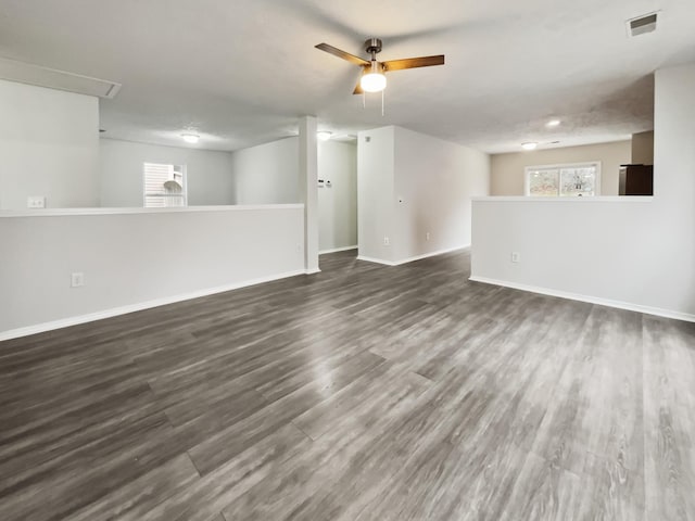 unfurnished living room with dark wood-style floors, visible vents, and baseboards