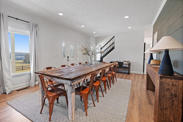 dining space with visible vents, a textured ceiling, and light wood-style flooring
