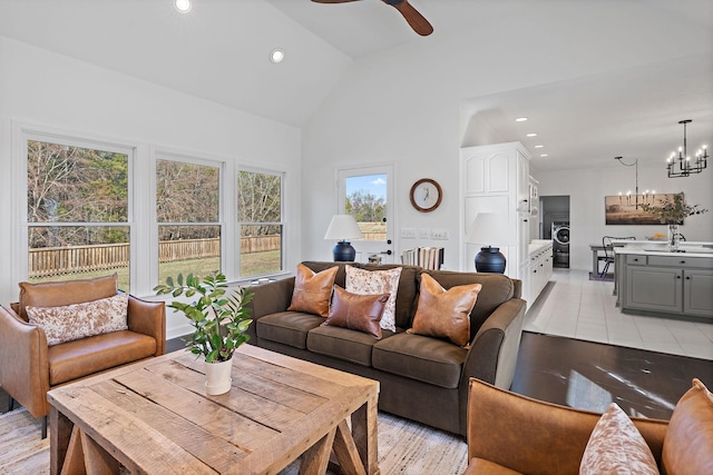 living room with light tile patterned floors, washer / dryer, recessed lighting, ceiling fan with notable chandelier, and high vaulted ceiling