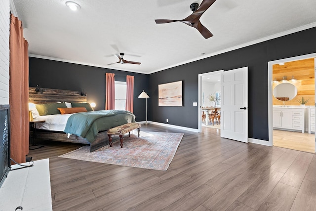 bedroom with ornamental molding, connected bathroom, baseboards, and wood finished floors