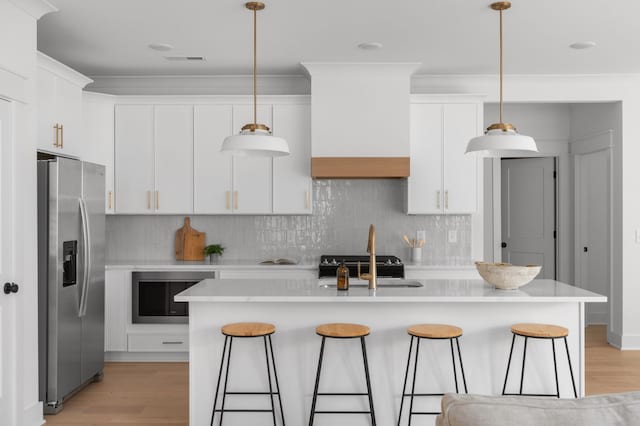 kitchen with light countertops, a kitchen breakfast bar, stainless steel fridge with ice dispenser, and light wood-type flooring