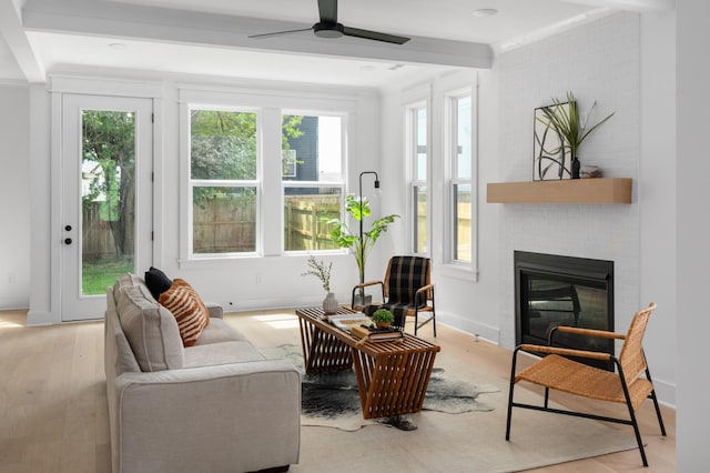 living room featuring a ceiling fan, baseboards, light wood-style flooring, a fireplace, and ornamental molding