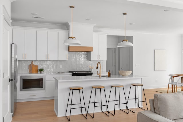 kitchen featuring backsplash, white cabinetry, a breakfast bar area, built in microwave, and stove