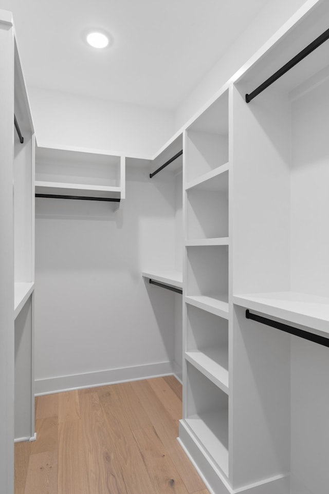 walk in closet with light wood finished floors