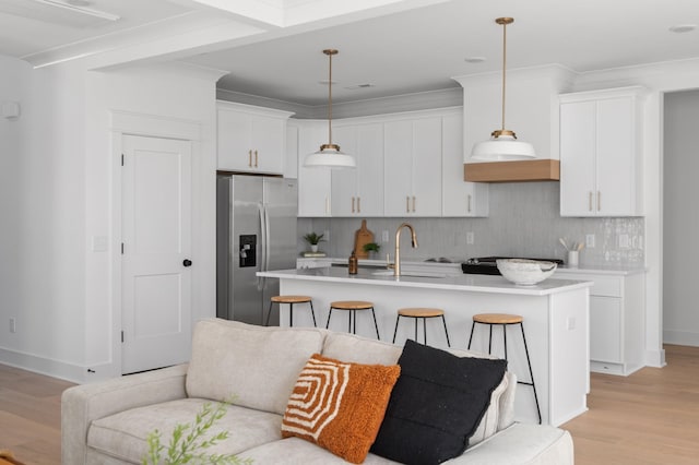 kitchen with light countertops, white cabinets, stainless steel refrigerator with ice dispenser, and a sink