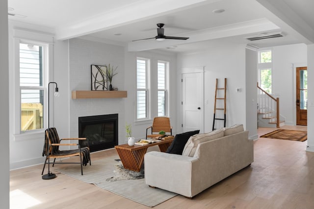 living room featuring visible vents, a brick fireplace, beamed ceiling, stairs, and wood finished floors