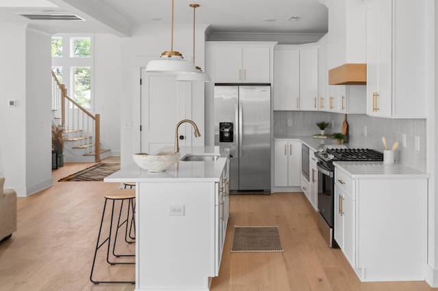 kitchen featuring light wood-style flooring, a sink, light countertops, appliances with stainless steel finishes, and backsplash