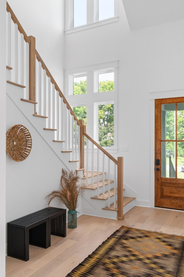 entrance foyer with wood finished floors, a towering ceiling, and stairs