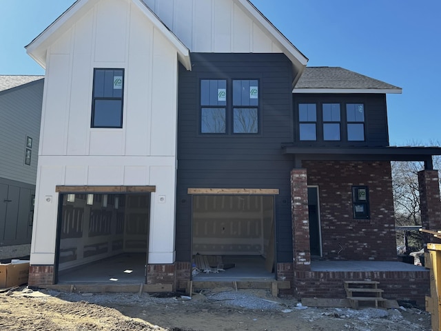 modern farmhouse style home with a garage, brick siding, board and batten siding, and a shingled roof