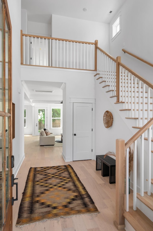 entrance foyer featuring a wealth of natural light, stairway, wood finished floors, and a towering ceiling