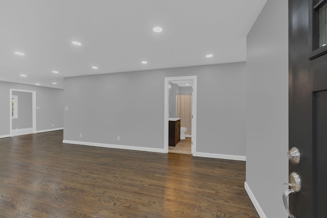 empty room with dark wood finished floors, recessed lighting, and baseboards