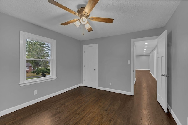 unfurnished bedroom with dark wood-style floors, a textured ceiling, baseboards, and a ceiling fan