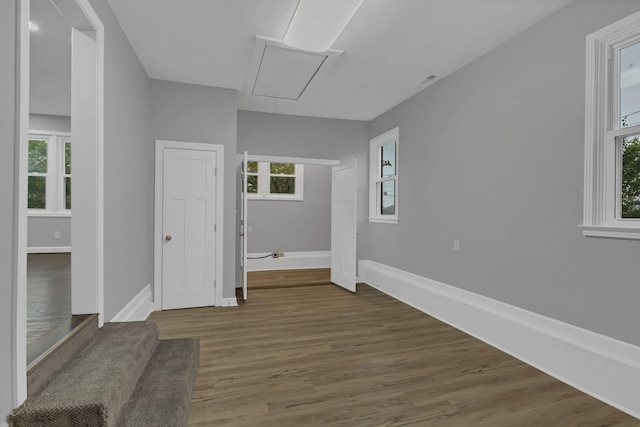 unfurnished room with attic access, baseboards, and wood finished floors