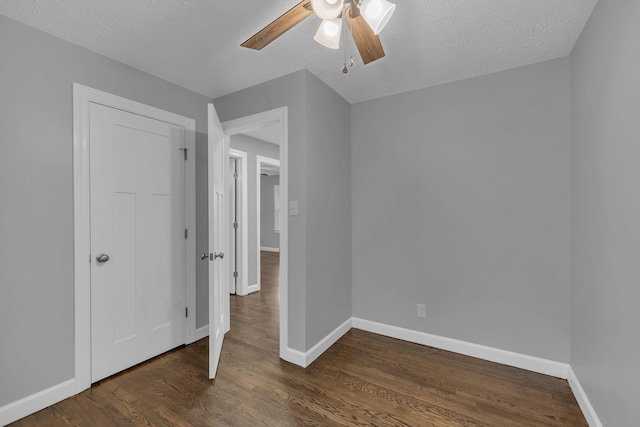 unfurnished bedroom with dark wood-style floors, a textured ceiling, and baseboards