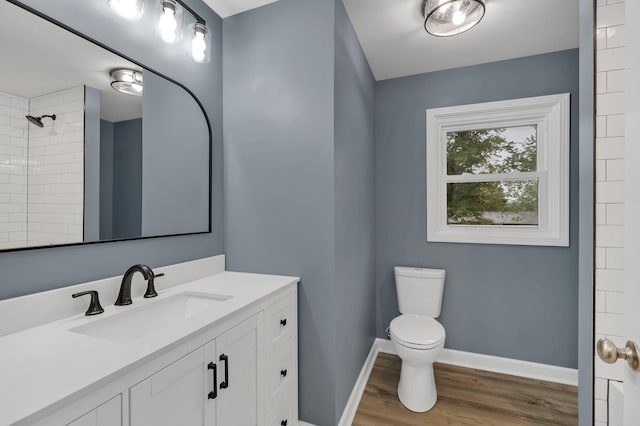 full bath featuring baseboards, toilet, wood finished floors, vanity, and a shower