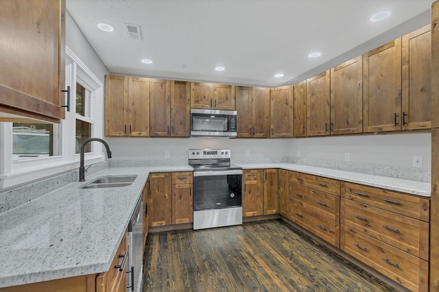 kitchen with a sink, dark wood-style floors, recessed lighting, stainless steel appliances, and light stone countertops