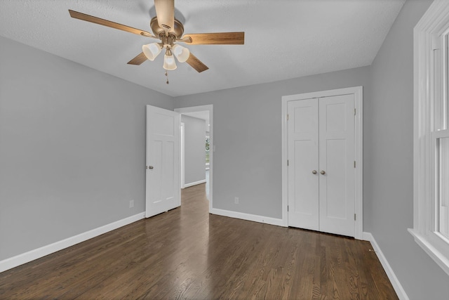 unfurnished bedroom featuring ceiling fan, a closet, baseboards, and dark wood-style floors