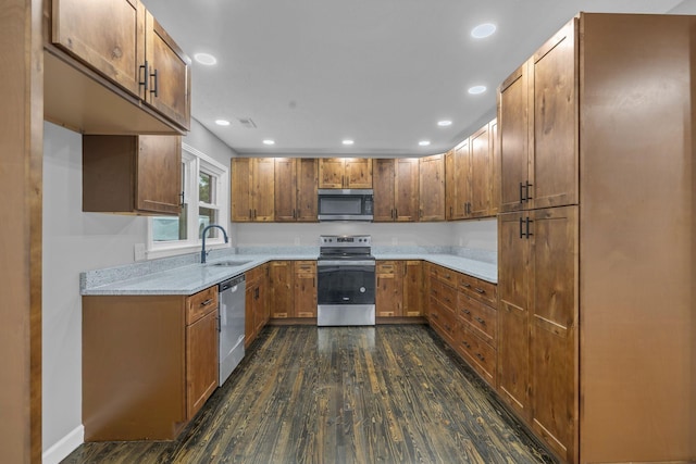 kitchen featuring brown cabinets, a sink, dark wood-style floors, appliances with stainless steel finishes, and light countertops