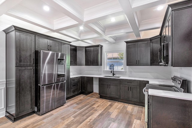 kitchen featuring a sink, beamed ceiling, light wood-style floors, and stainless steel appliances