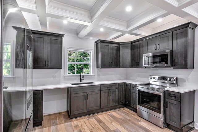 kitchen with coffered ceiling, beam ceiling, light wood-style flooring, a sink, and appliances with stainless steel finishes