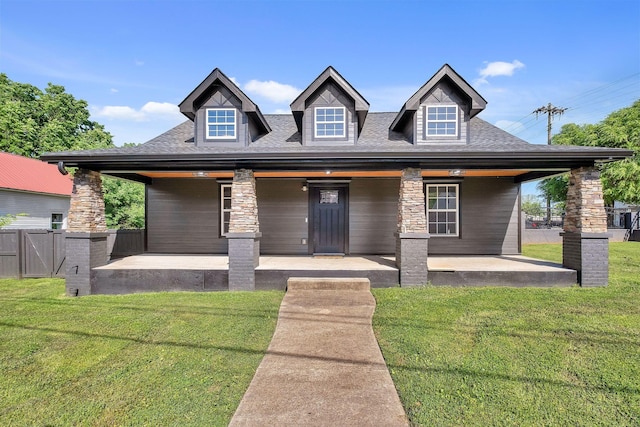 view of front facade featuring a front yard, a patio area, fence, and roof with shingles