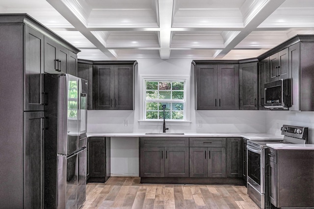 kitchen with light countertops, light wood-style flooring, beamed ceiling, and appliances with stainless steel finishes