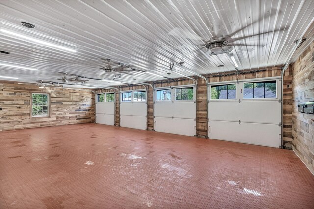 garage featuring ceiling fan and wood walls