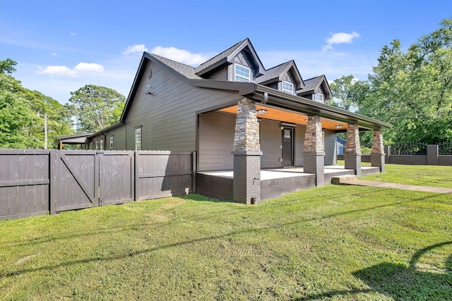 view of side of home with a patio, a yard, fence, and stone siding