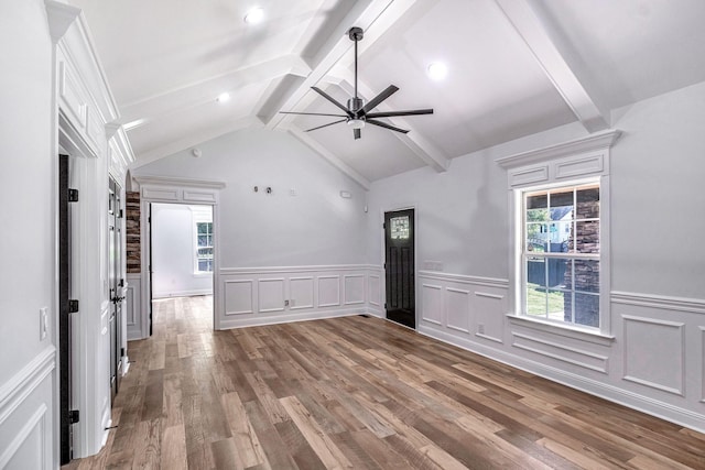 spare room featuring a wealth of natural light, wood finished floors, and vaulted ceiling with beams