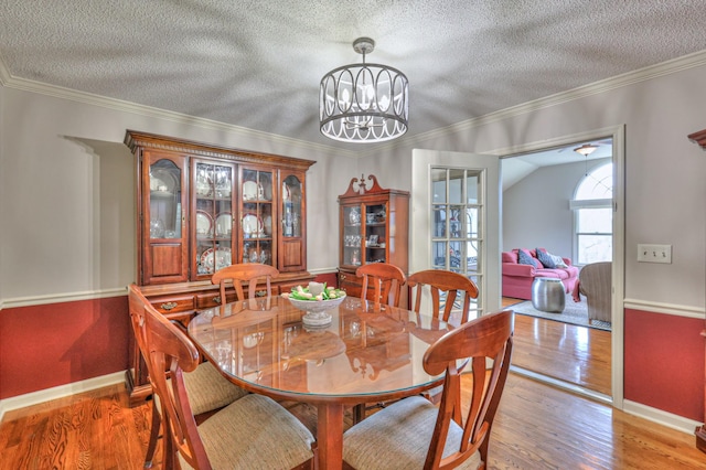 dining space featuring a textured ceiling, an inviting chandelier, wood finished floors, and crown molding